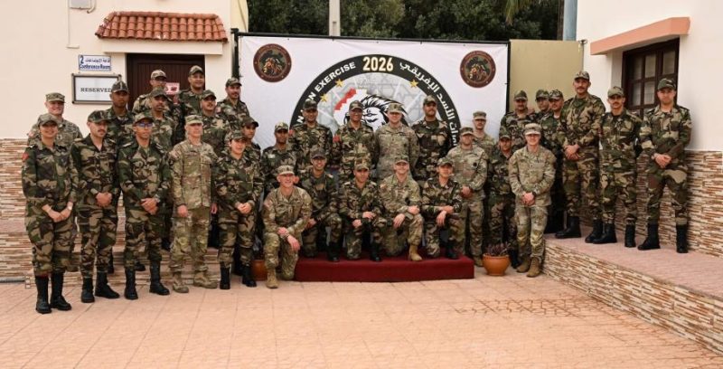 vis_0424202623401392 | MCG24 | موقع إلكتروني مغربي شامل متجدد على مدار الساعة Group of soldiers in camouflage uniforms pose for a photo in front of a banner marked 2026 during a military exercise.