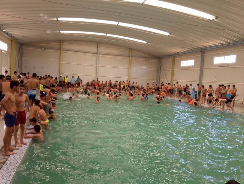 FB_IMG_1779639592554 | MCG24 | موقع إلكتروني مغربي شامل متجدد على مدار الساعة Large indoor swimming pool filled with children and adults along the edges and swimming in the water.