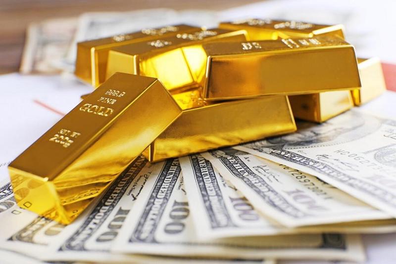 Gold-Dollar | MCG24 | موقع إلكتروني مغربي شامل متجدد على مدار الساعة Gold bullion bars stacked on top of US hundred-dollar bills, symbolizing wealth and investment.