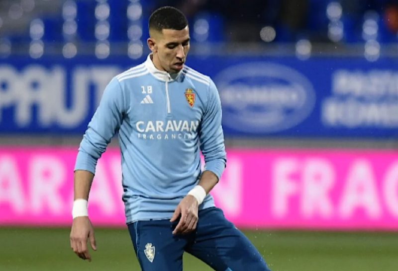 IMG_3229 | MCG24 | موقع إلكتروني مغربي شامل متجدد على مدار الساعة Soccer goalkeeper in a light blue jersey with white wristbands, standing on a grass field during a match warm-up