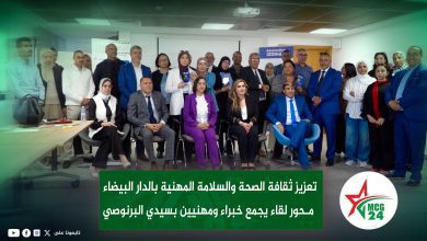 Group of diverse professionals posing for a photo in a conference room, with banners and logos in the background.