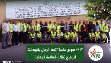 Group of men in high‑visibility vests posing for a training photo in front of a banner and logo on a wall.