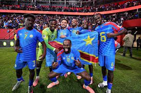 téléchargement 29 | MCG24 | موقع إلكتروني مغربي شامل متجدد على مدار الساعة Group of soccer players in blue jerseys with yellow stars celebrate on the field, some kneeling, after a match.