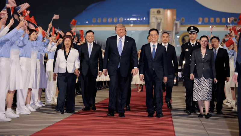 trump | MCG24 | موقع إلكتروني مغربي شامل متجدد على مدار الساعة Delegation arrives on a red carpet at an airport, led by a central group of leaders with flag‑bearing attendants nearby.