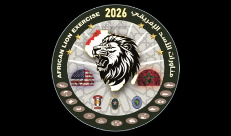 vis_0504202617004962 | MCG24 | موقع إلكتروني مغربي شامل متجدد على مدار الساعة Circular emblem for African Lion Exercise 2026 featuring a roaring lion at center, with flags and unit insignia on a dark background