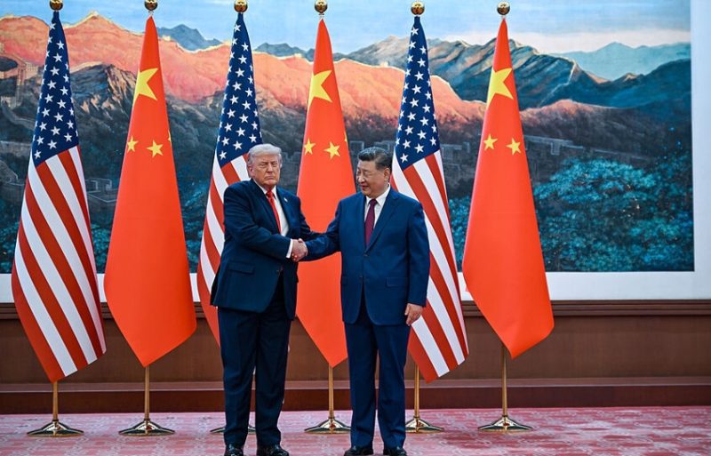 vis_0514202616581477 | MCG24 | موقع إلكتروني مغربي شامل متجدد على مدار الساعة Two world leaders, Donald Trump and Xi Jinping, shake hands in front of alternating US and China flags during a formal meeting backdrop of mountains and a gallery wall.