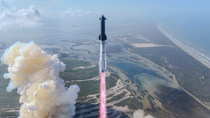 Rocket launches upright from coast, pink exhaust plume rising over marshlands and sea.