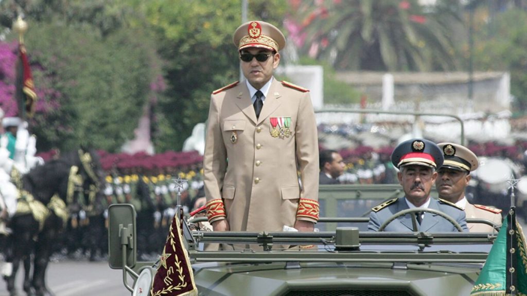 القوات-المسلحة-الملكية | MCG24 | موقع إلكتروني مغربي شامل متجدد على مدار الساعة Uniformed officer standing in an open-top military vehicle during a parade, medals on his chest with other officers in the background.