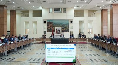 1000263336 | MCG24 | موقع إلكتروني مغربي شامل متجدد على مدار الساعة Large conference room with officials seated around U-shaped tables; a data presentation board sits at the front in the foreground.
