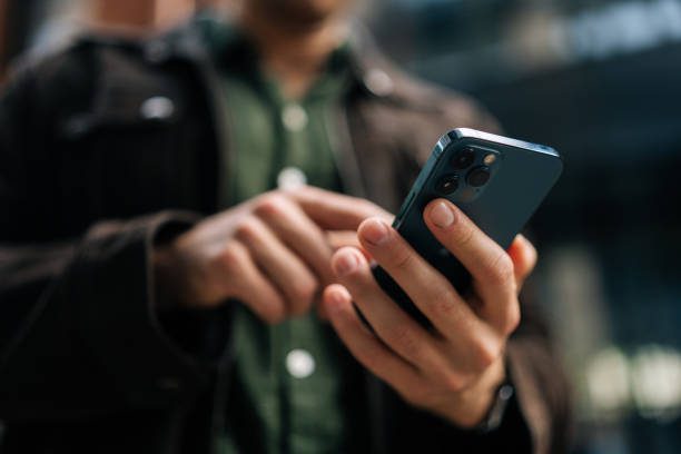 Person holding and using a blue smartphone outdoors, focusing on the device in their hands.
