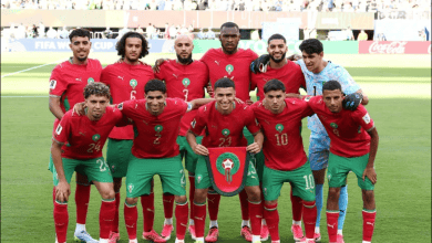 6a3439b057219 | MCG24 | موقع إلكتروني مغربي شامل متجدد على مدار الساعة Morocco national football team players pose for a pre-match photo on a green pitch, holding the team crest shield.