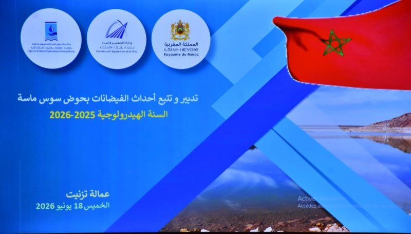 85900c82-f665-4d0d-95a4-294ac8fccb6a | MCG24 | موقع إلكتروني مغربي شامل متجدد على مدار الساعة Blue promotional banner for a Moroccan government event, with three circular logos at the top, a waving Moroccan flag on the right, and Arabic text mentioning the years 2025–2026 and 18 June 2026 in the bottom-left area.