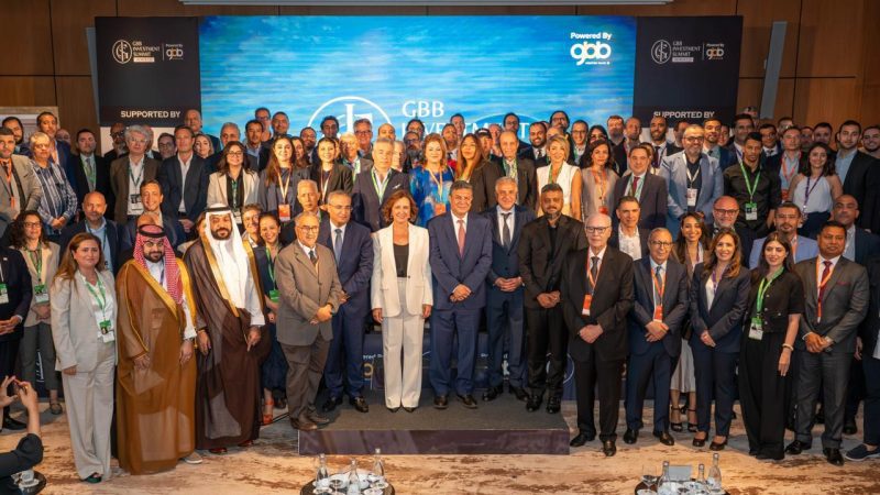 Hospitality-Innovation-Summit | MCG24 | موقع إلكتروني مغربي شامل متجدد على مدار الساعة Group photo of diverse conference attendees and dignitaries on stage in front of a blue event backdrop with logos and banner text. Front row features suited men and women, including individuals in traditional Middle Eastern dress, posing for the portrait.