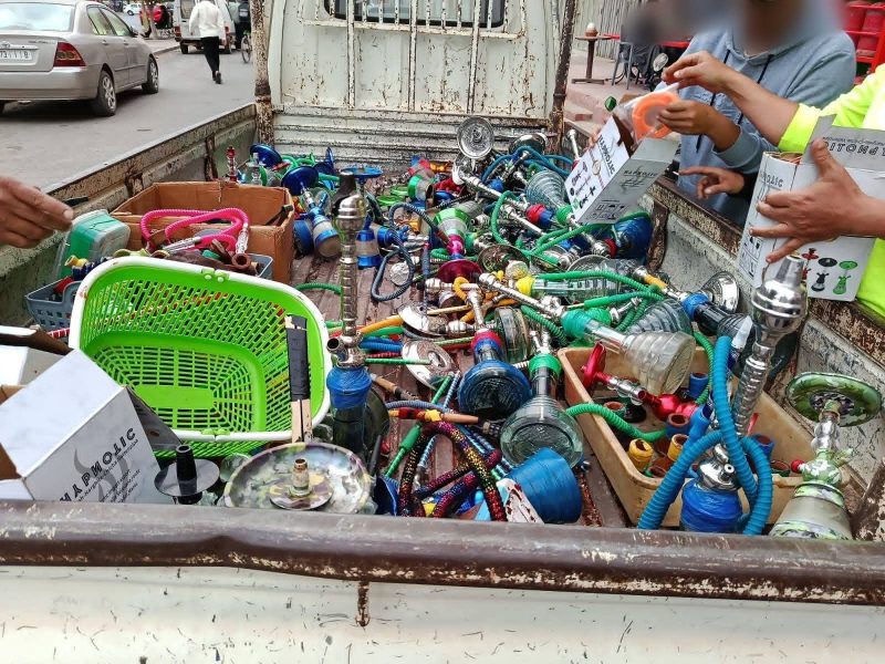 IMG-20260610-WA0344 | MCG24 | موقع إلكتروني مغربي شامل متجدد على مدار الساعة Pickup truck bed overflowing with colorful hookah hoses, bowls, and accessories, as vendors handle boxes and items nearby