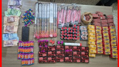 IMG-20260619-WA0290 | MCG24 | موقع إلكتروني مغربي شامل متجدد على مدار الساعة Display of seized items on a table: bundled cash, a smartphone, colorful wrapped fireworks and various packaged goods arranged in rows as evidence.
