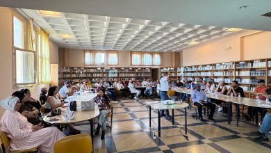 IMG-20260620-WA0092 | MCG24 | موقع إلكتروني مغربي شامل متجدد على مدار الساعة Group of people seated around tables in a library, listening to a presenter standing at the front.