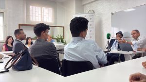 WhatsApp Image 2026-06-21 at 185259 | MCG24 | موقع إلكتروني مغربي شامل متجدد على مدار الساعة Group of people in a meeting room listening to two speakers at the front with a laptop and a green microphone on the table.