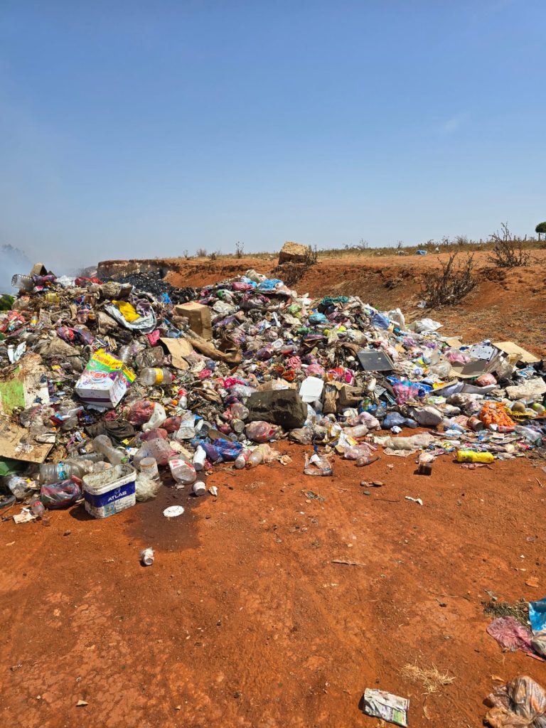حرق عشوائي للأزبال بالمنصورية يثير غضب الساكنة ومطالب بفتح تحقيق عاجل Pile of trash and litter on red dirt under a clear blue sky at a dumpsite.