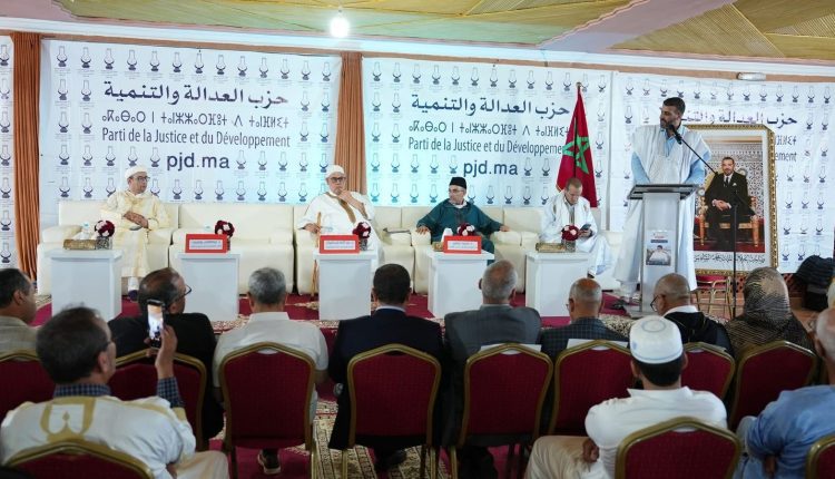 da079097-9f68-43ef-948d-6dde1d1f816d-750x430 | MCG24 | موقع إلكتروني مغربي شامل متجدد على مدار الساعة Panel of five men seated on a stage during a political conference; Moroccan flag visible and banners for the Party of Justice and Development (PJD) in Arabic and French.