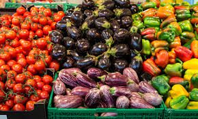 22115454484 | MCG24 | موقع إلكتروني مغربي شامل متجدد على مدار الساعة Colorful display of fresh vegetables at a market: tomatoes, purple eggplants, purple onions, and green and yellow bell peppers in crates.