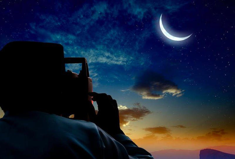 سنة-سعيدة | MCG24 | موقع إلكتروني مغربي شامل متجدد على مدار الساعة Silhouette of a person taking a photo of a crescent moon in a starry night sky.