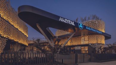 Modern hospital exterior at dusk with a curved canopy and illuminated AKDITAL Anfa Prime Hospital sign against a honeycomb-lit facade