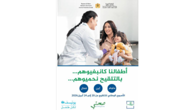 Poster of a nurse discussing with a smiling mother and her baby in a clinic, promoting child immunization in Arabic text
