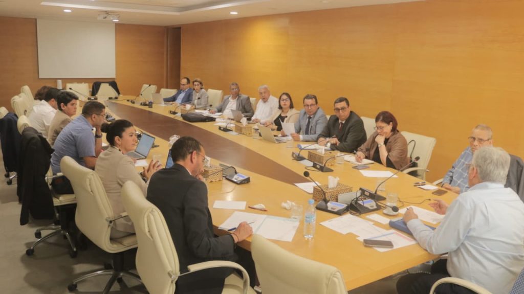 WhatsApp Image 2026-04-23 at 122053 | MCG24 | موقع إلكتروني مغربي شامل متجدد على مدار الساعة Group of professionals seated around a large conference table in a meeting room, discussing with laptops and documents on the table.