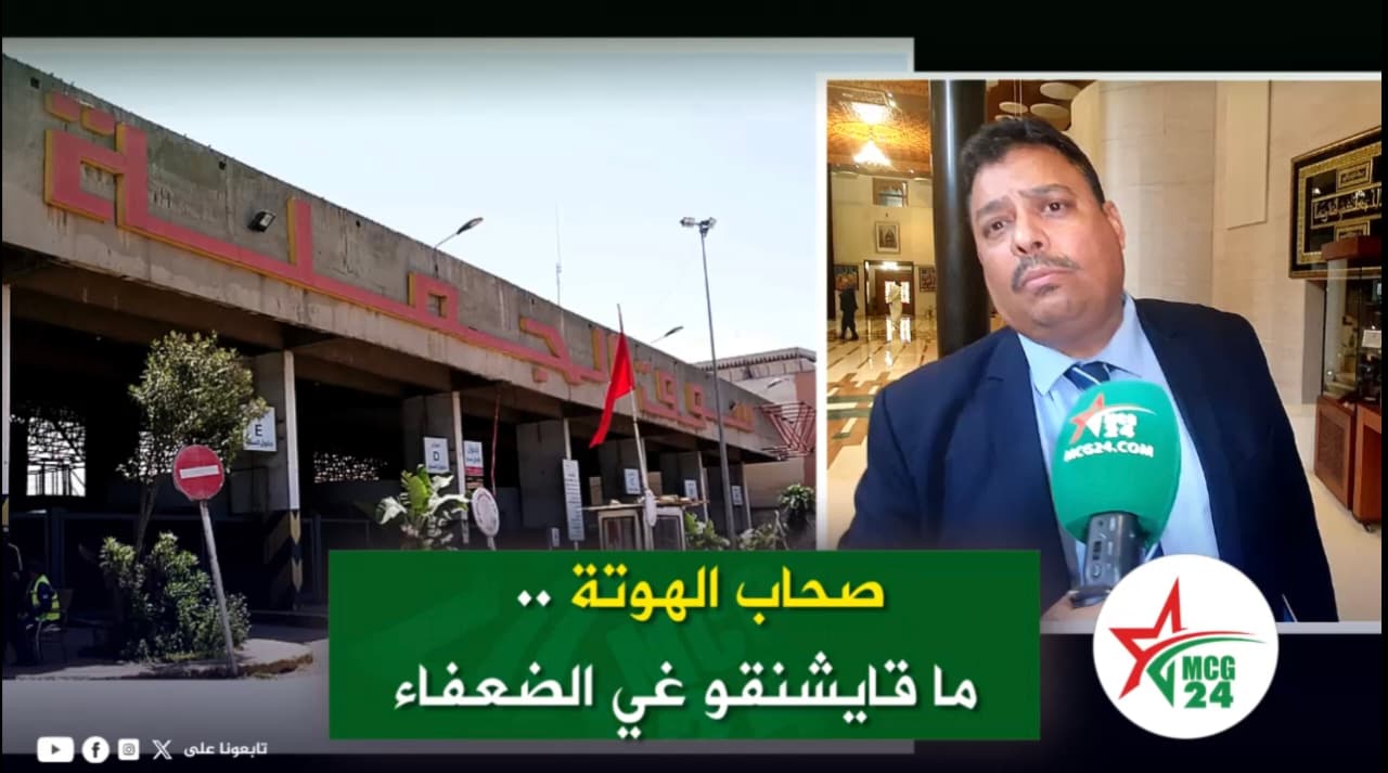 Split-screen video thumbnail: left side shows a concrete public building with red signage and a flag; right side shows a man in a suit being interviewed with a green microphone, overlaid by a green caption banner with Arabic text.