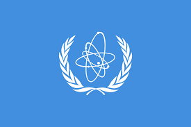 White emblem featuring an atomic model surrounded by laurel branches on a blue background.