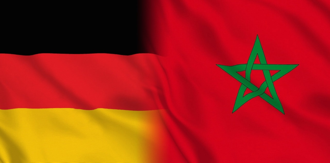 Germany flag on the left and Morocco flag on the right, showing black-red-gold stripes beside a red field with a green pentagram, representing two nations side by side on one image.