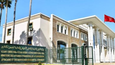 Exterior of the Moroccan Ministry of Foreign Affairs building with a gated entrance, beige stone, and a Moroccan flag flying