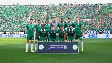 Soccer team in green jerseys posing for a group photo on the field with a banner reading COTE-SPORT and a packed green-clad stadium behind them **(informative image).