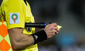 Referee in a neon yellow uniform writes on a sticky note while on the sidelines.
