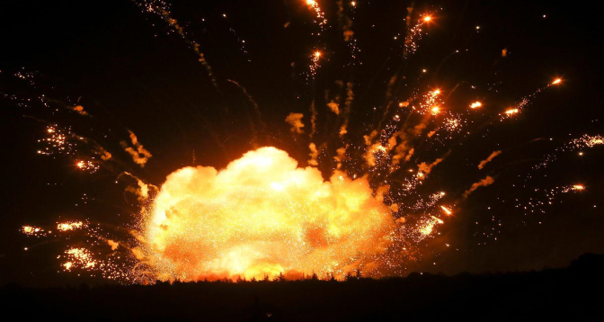 Nighttime explosion: a large orange fireball blasting from the ground with sparks streaming outward.