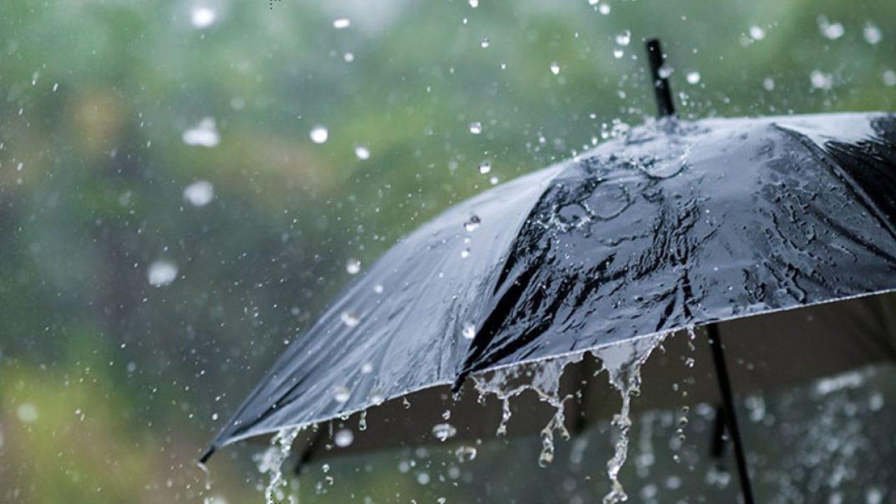 Black umbrella glistening with rain droplets as water splashes around in a rainy scene
