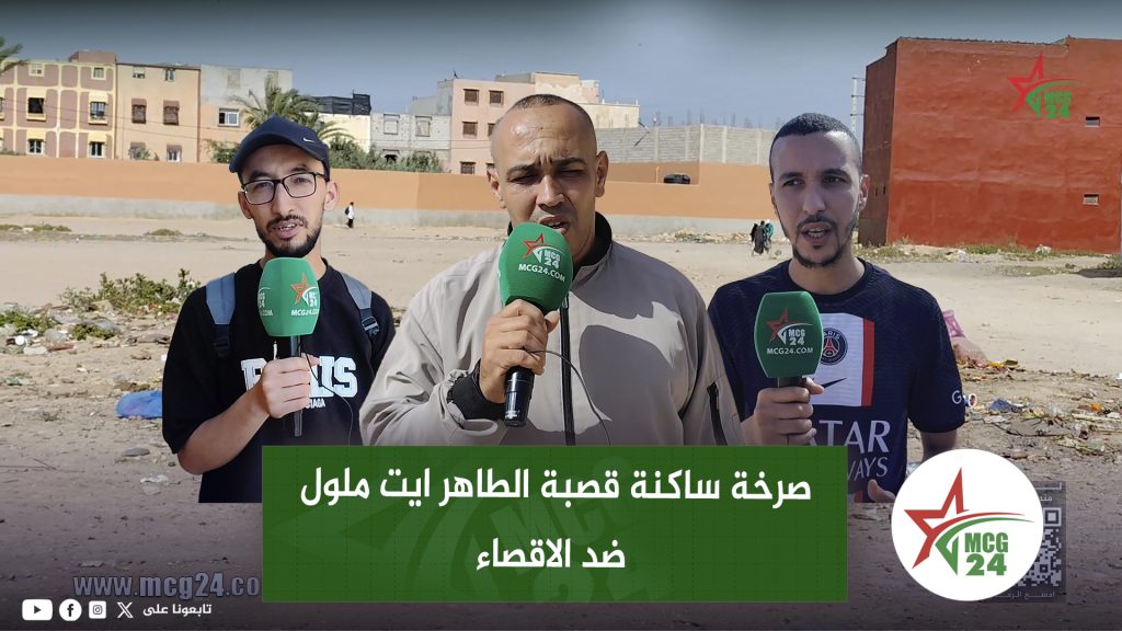 صرخة ساكنة قصبة الطاهر ايت ملول ضد الاقصاء ” حصيلة مجلس جماعة أيت ملول بالقصبة صفر مشروع “ Three male reporters stand outdoors with green MCG24 microphones, filming a report in a dusty area with buildings behind. Arabic headline overlay visible.