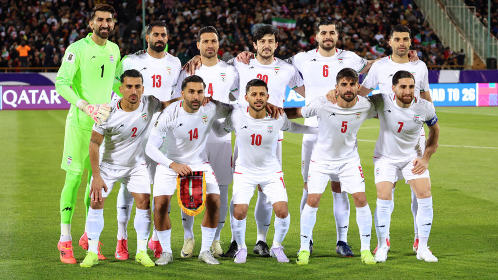 000-99QT9WE | MCG24 | موقع إلكتروني مغربي شامل متجدد على مدار الساعة Iran national football team posing for a group photo on the field; goalkeeper in neon green stands at the left.