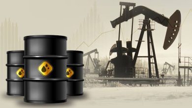 1-4 | MCG24 | موقع إلكتروني مغربي شامل متجدد على مدار الساعة Stacks of black oil barrels with a yellow hazard label in the foreground, and silhouettes of oil pumpjacks in a distant field.