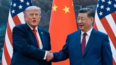 Donald Trump and Xi Jinping shake hands in front of US and Chinese flags.