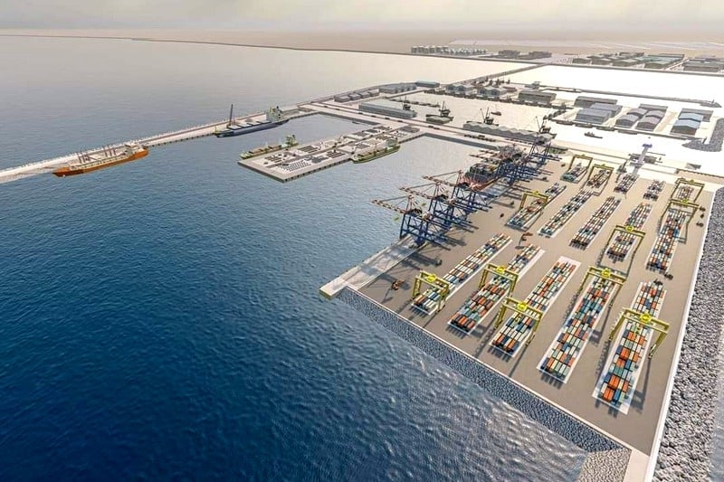 Aerial view of a large container port with stacked shipping containers, gantry cranes, and docked ships along the pier.