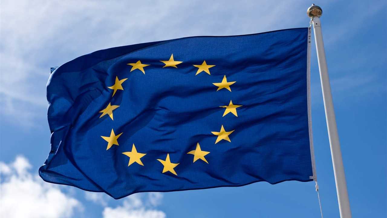 European Union flag waving in the wind against a blue sky.