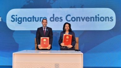 1778086897036 1 | MCG24 | موقع إلكتروني مغربي شامل متجدد على مدار الساعة Two professionals in suits stand behind a desk, holding red ceremonial folders during a signing ceremony.