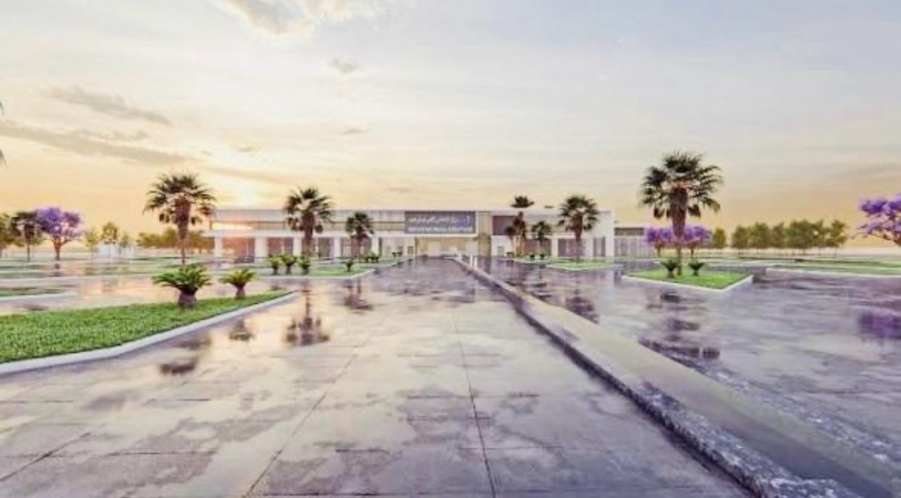 1778331219996 | MCG24 | موقع إلكتروني مغربي شامل متجدد على مدار الساعة Wide, modern building at the end of a reflective marble plaza lined with palm trees, at sunset.