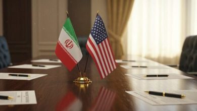 Diplomatic conference table with Iran and United States flags at center, papers and pens nearby
