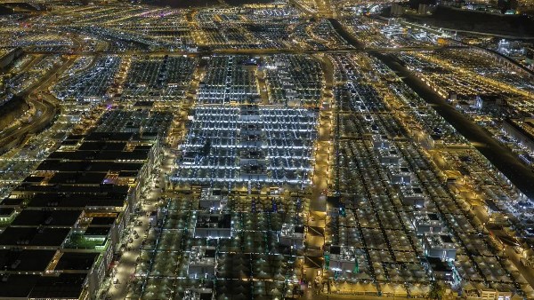 Aerial night view of a dense city grid with illuminated streets and block-shaped neighborhoods, viewed from above at night.