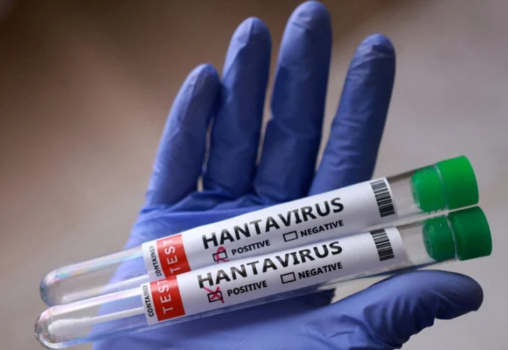 Gloved hand holding two test tubes labeled hantavirus with positive and negative checkboxes, in a lab setting.