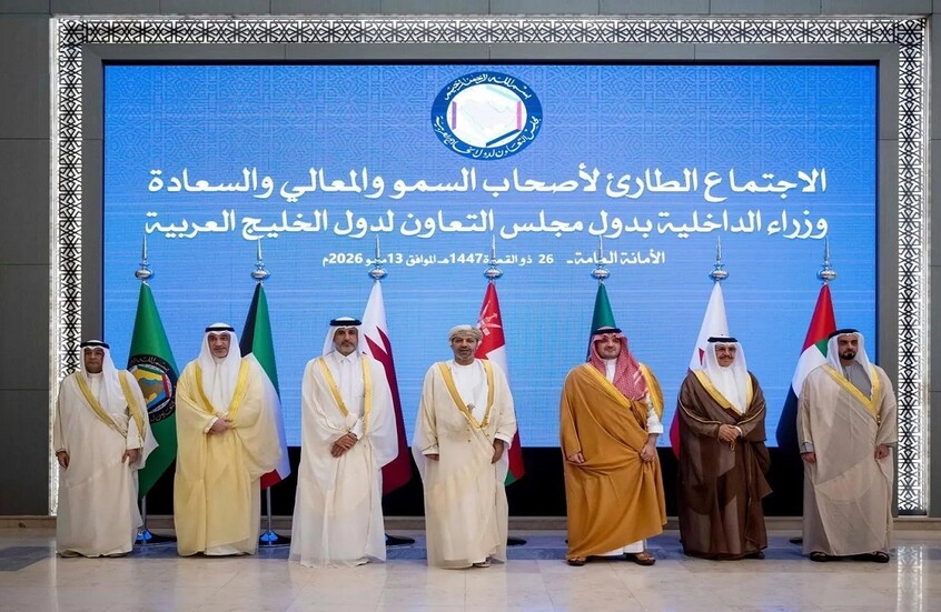 Group of dignitaries in traditional Gulf attire standing on stage for a diplomatic summit with a blue backdrop and Arabic text behind them.
