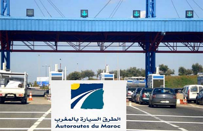85845059-61141595 | MCG24 | موقع إلكتروني مغربي شامل متجدد على مدار الساعة Toll plaza on a highway with several lanes and cars, blue structures, and a sign reading 'Autoroutes du Maroc' in Arabic and French.
