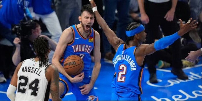 8739649_1779340543 | MCG24 | موقع إلكتروني مغربي شامل متجدد على مدار الساعة Thunder players in blue uniforms share an intense moment on the court; one guards the ball and shouts while a teammate raises an arm, opposing white #24 watches.